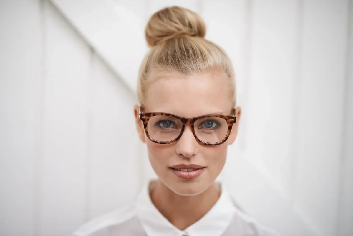 A young woman wearing a blouse and glasses